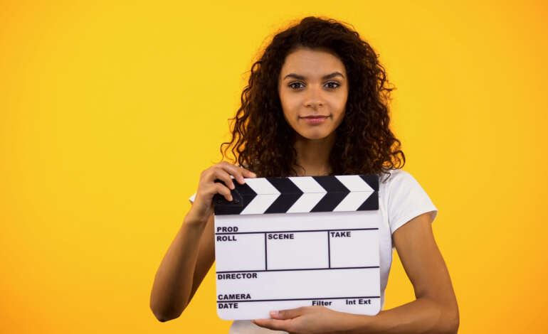Young woman holding a clapper board and filming brand identity videos