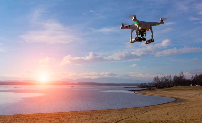 A drone overlooks the beach at sunset, capturing drone footage for a video production.