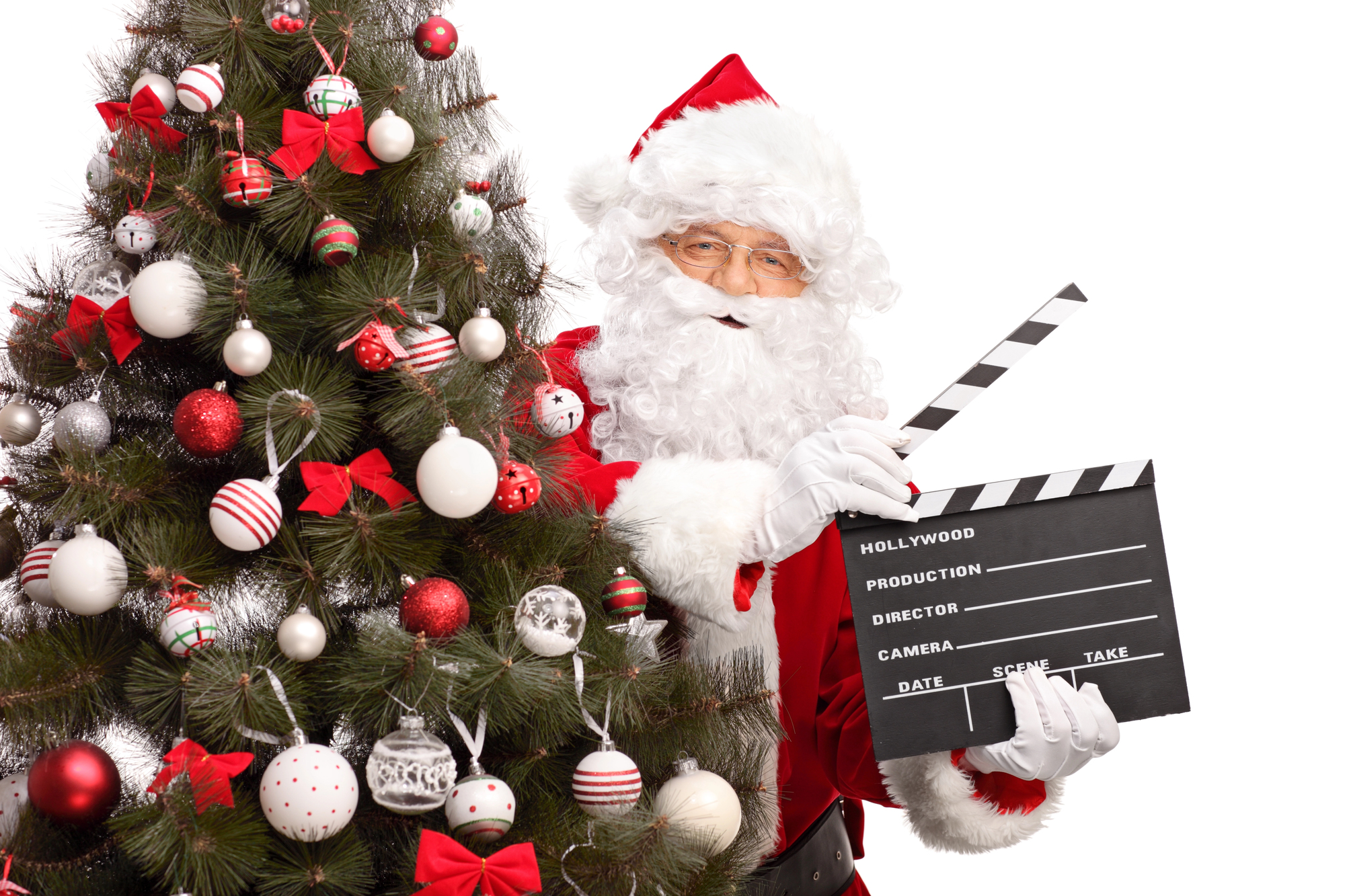 Santa Claus posing with a clapperboard and Christmas tree to film holiday video campaigns.