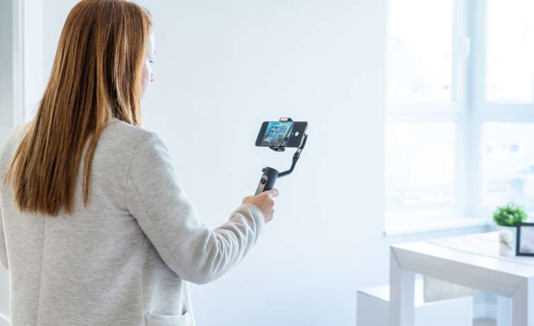 A female realtor using real estate video production to film a property tour on her smartphone.