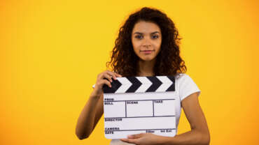 Young woman holding a clapper board and filming brand identity videos