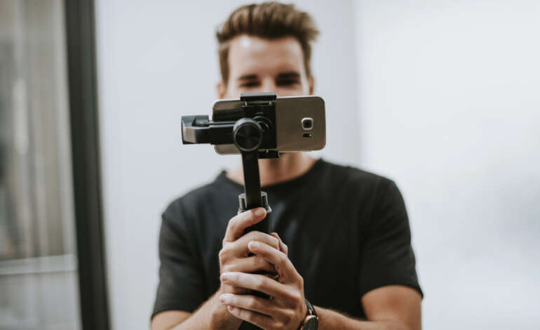 Man holding a gimbal attached to a smartphone.