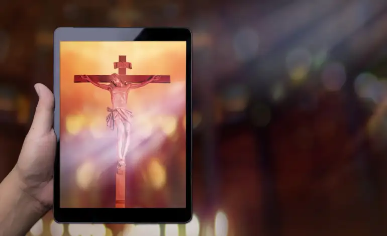 Hand holding a tablet displaying a picture of Jesus on the cross.